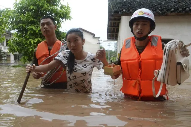 Rescuers help a woman get to dry area as they walk among floodwater after heavy rainfall hit Chongqing municipality, September 13, 2014. At least 10 people died after severe downpours battered southwest China's Sichuan Province and Chongqing Municipality, Xinhua News Agency reported. (Photo by Reuters/Stringer)