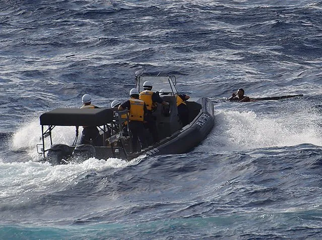 This handout picture taken on August 11, 2016 and released by the Japanese Coast Guard shows coast guards in an inflatable speedboat rescuing a crew member of a Chinese fishing boat near the waters of disputed East China Sea islands. Japan is searching for eight Chinese crew members who went missing when their fishing boat sank after colliding with a Greek cargo vessel near disputed East China Sea islands on August 11, the Japanese coast guard said. (Photo by AFP Photo/Japan Coast Guard)