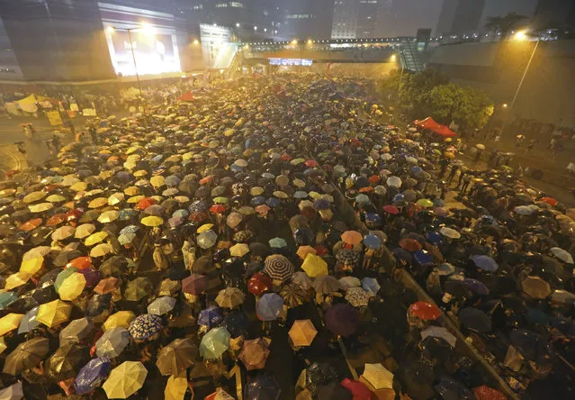 Pro-democracy protesters hold umbrellas under heavy rain in a main street near the government headquarters in Hong Kong late Tuesday, September 30, 2014. The protesters demanded that Hong Kong's top leader meet with them on Tuesday and threatened wider actions if he did not, after he said China would not budge in its decision to limit voting reforms in the Asian financial hub. (Photo by AP Photo)