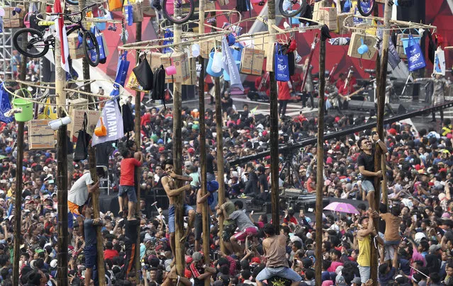 Participants struggle during a greased-pole climbing competition held as a part of independence day celebration at Ancol Beach in Jakarta, Indonesia, Thursday, August 17, 2017. Contestants race up to grab items ranging from buckets to bicycles hanging from the top of the poles as prize. Indonesia is celebrating its 72th anniversary of independence from the Netherlands. (Photo by Achmad Ibrahim/AP Photo)