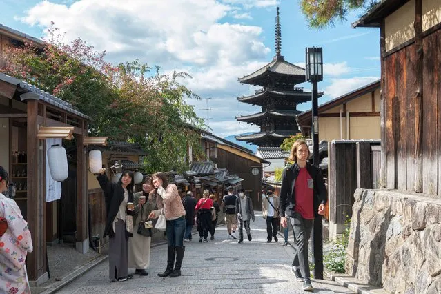 People stroll along the stone-paved pedestrianised Sannen-zaka, a popular tourist area in Kyoto on October 11, 2022. Japan reopened its doors to tourists on October 11 after two-and-a-half years of tough Covid-19 restrictions, with officials hoping an influx of travellers enticed by a weak yen will boost the economy. (Photo by Fred Mery/AFP Photo)