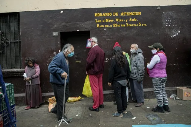 People wait in a line to receive free food at La Parada market in La Victoria district of Lima, Peru, Tuesday, June 23, 2020. Many businesses reopened Monday in Peru after a mandatory closure that began on March 16 with the start of a quarantine aimed at slowing the advance of the new coronavirus. (Photo by Rodrigo Abd/AP Photo)