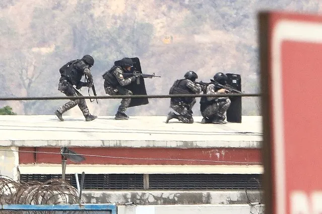 Members of the elite police take up position on the roof of the Guayas 1 prison during an operative to control a riot in Guayaquil, Ecuador, on November 3, 2022. (Photo by Gerardo Menoscal/AFP Photo)