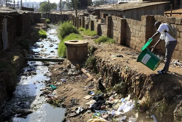 A student empties a dustbin next to a murky stream near a school in Kenya's Kibera slums in capital Nairobi, September 21, 2015. Kenya's president on Sunday urged teachers who have been on strike for about three weeks to return to work, saying their demand for a pay rise of up to 60 percent could not be met. (Photo by Noor Khamis/Reuters)