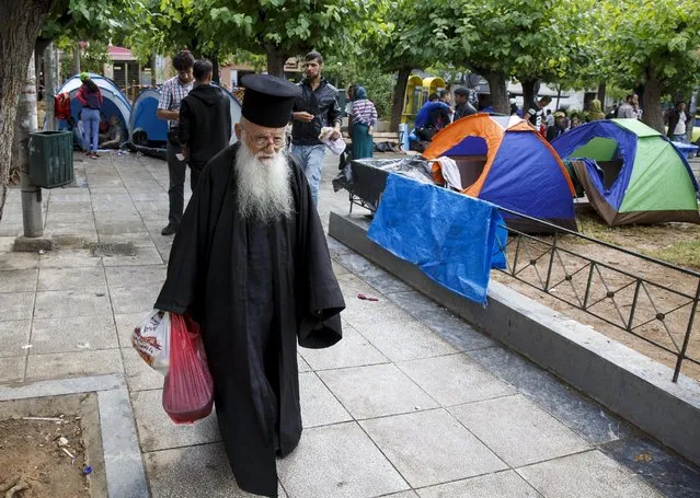 A Greek Orthodox priest walks past tents of Afghan refugees in Victoria square, where hundreds of migrants and refugees sleep rough, in central Athens, Greece, September 22, 2015. Interior ministers from the European Union were gathering in Brussels on Tuesday to try to break a deadlock on sharing out asylum-seekers that has plunged the 28 member states into a fury of mutual recriminations. (Photo by Paul Hanna/Reuters)
