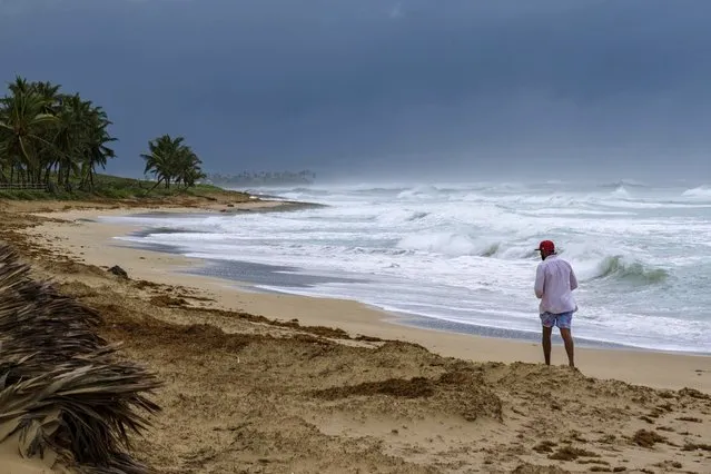 A man walks on the beach next to waves kicked up by Hurricane Fiona in Punta Cana, Dominican Republic, Monday, September 19, 2022. (Photo by Ricardo Hernandez/AP Photo)