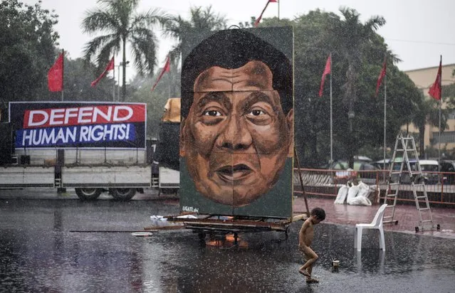 A child play as it rains during a protest in Manila on December 10, 2017, as activists commemorate the International Human Rights Day. Philippine President Rodrigo Duterte on December 5 told human rights groups  to “go to hell” after ordering police back to the front lines of the drug crackdown. (Photo by Noel Celis/AFP Photo)