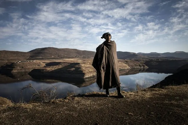 This file photo taken on July 13, 2016 shows Ntoaesele Mashongoane, a 32 years old shephard, calling his sheep as he stands in front of the controversial Katse dam, which only provides water to South Africa on July 13, 2016 in Katse. Farmers in Lesotho have been struggling with an almost year long drought that has devastated crops and left rural areas without water. (Photo by John Wessels/AFP Photo)
