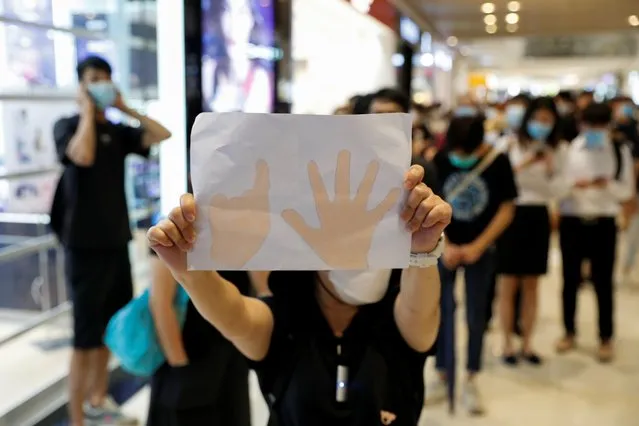 A pro-democracy demonstrator holds a paper with a symbol of “Five demands, not one less” during a protest to mark the first anniversary of an attack in a train station by an armed crowd wearing white shirts, demanding justice for the victims of violence and broader freedoms, at a shopping mall in Hong Kong's Yuen Long, China on July 21, 2020. (Photo by Tyrone Siu/Reuters)