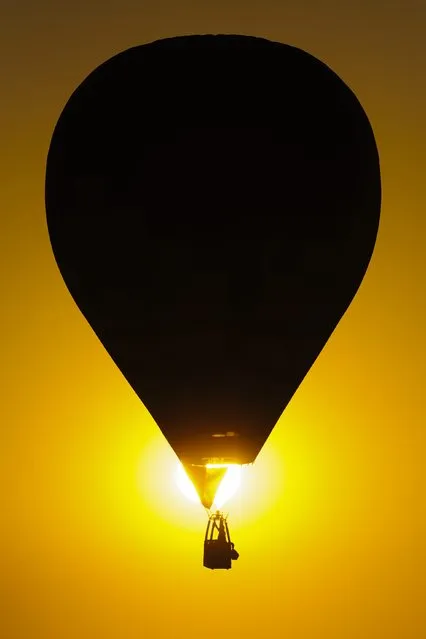 A hot air balloon flies during sundown at the 19th FAI Hot Air Balloon European Championships in Debrecen, 226 kms east of Budapest, Hungary, Tuesday, August 11, 2015. (Photo by Zsolt Czegledi/MTI via AP Photo)