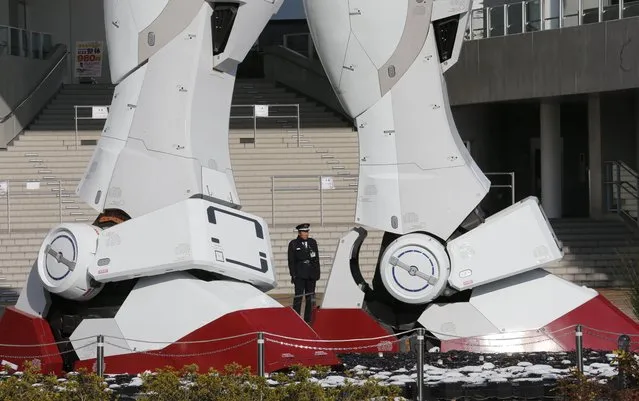 A security officer stands at the legs of a giant model of Japan’s popular robot animation character Gundam in Tokyo,Tuesday, January 15, 2013. (Photo by Koji Sasahara/AP Photo)