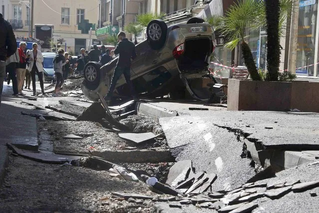People look at an overturned car in the street that was damaged in flooding caused by torrential rain in Cannes, France, October 4, 2015. (Photo by Eric Gaillard/Reuters)