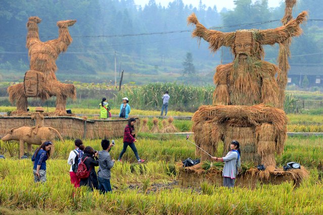 Tourists take pictures of straw figurines of traditional deities Shennong (R) and Zhang Wulang (L back) during China's National Day Holiday, in Xinhua county, Hunan province, October 4, 2015. (Photo by Reuters/China Daily)
