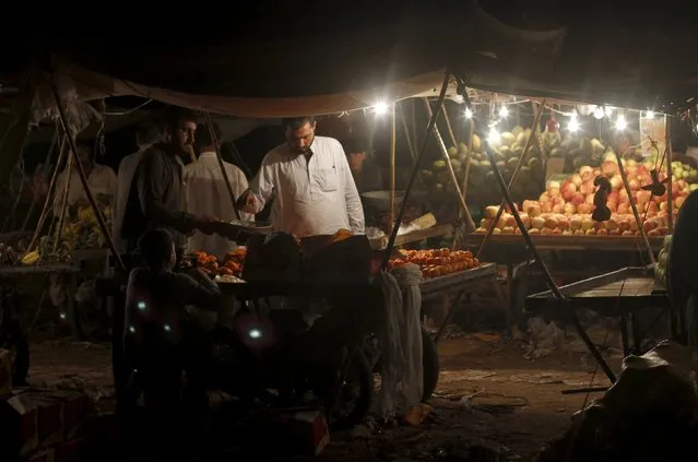 A pomegranate seller serves a customer from his roadside cart in Karachi, Pakistan October 2, 2015. (Photo by Athar Hussain/Reuters)