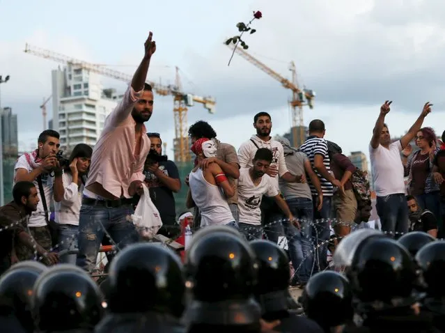 A protester throws a flower over barbed wire as riot policemen block a street leading to the parliament building during a protest against perceived government failures, including a rubbish disposal crisis, in downtown Beirut, Lebanon October 8, 2015. (Photo by Jamal Saidi/Reuters)