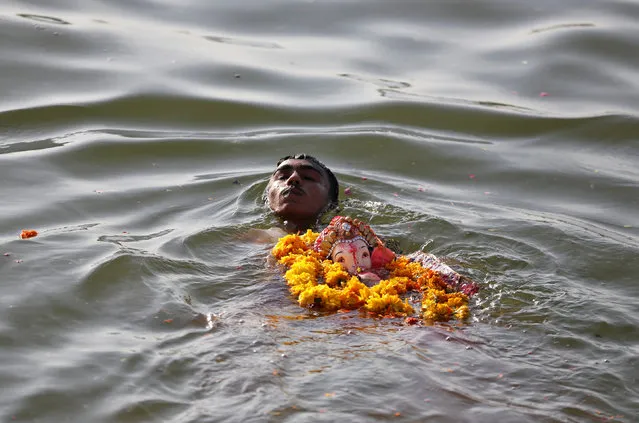A devotee immerses an idol of the Hindu god Ganesh, the deity of prosperity, in the Sabarmati river during the 10-day-long Ganesh Chaturthi festival in Ahmedabad, India, September 11, 2016. (Photo by Amit Dave/Reuters)
