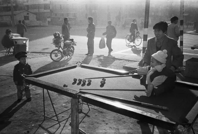 A child sitting on a roadside snooker pool plays with her mother in Beijing in 1983. (Photo by Reuters/China Daily)