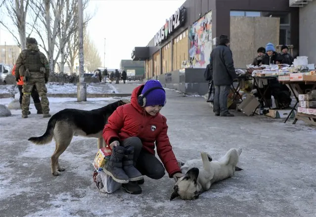 A local girl pets a dog at a street in Bakhmut, Donetsk region, eastern Ukraine, 09 January 2023, amid Russia's invasion. For months the front-line city of Bakhmut has seen heavy fighting taking place as it has been a key target for Russian forces. Russian troops on 24 February 2022, entered Ukrainian territory, starting a conflict that has provoked destruction and a humanitarian crisis. (Photo by Mykola Tymchenko/EPA/EFE)