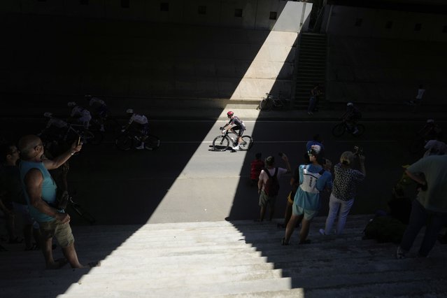 A competitor drives through a shaft of light during the eleventh stage of the Tour de France cycling race in Toulouse, France, Wednesday, July 16, 2025. (Photo by Mosa'ab Elshamy/AP Photo)