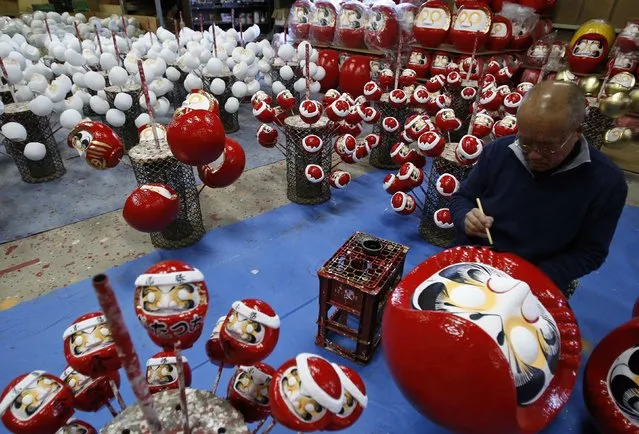 Japanese craftsman Sumikazu Nakata adds the final touches on a Daruma doll, which is believed to bring good luck, at his studio “Daimonya” in Takasaki, northwest of Tokyo November 23, 2014. (Photo by Yuya Shino/Reuters)