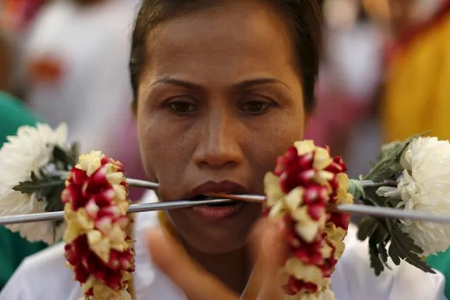 A devotee of the Chinese Jui Tui shrine walks with spikes pierced through her cheeks during a procession celebrating the annual vegetarian festival in Phuket, Thailand October 19, 2015. (Photo by Jorge Silva/Reuters)