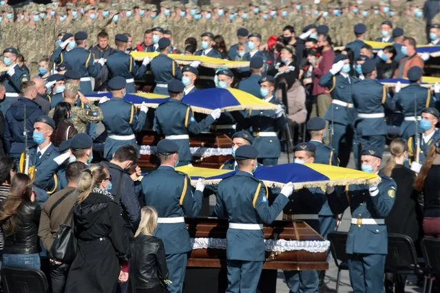 Servicemen cover the coffins of cadets of the Kharkiv National Air Force University who died in an Antonov An-26 transport plane crash with Ukrainian flags during a farewell ceremony at the central square in Kharkiv on October 6, 2020. (Photo by Sergey Bobok/AFP Photo)