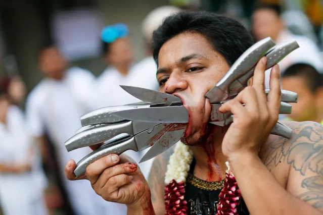 A devotee of the Chinese Ban Tha Rue shrine with knives piercing his face takes part in a procession celebrating the annual vegetarian festival in Phuket, Thailand October 5, 2016. (Photo by Jorge Silva/Reuters)