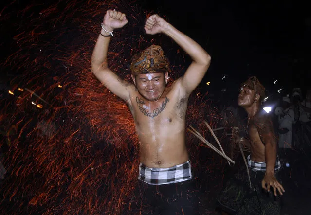 A Balinese man is hit with flaming coconut leaves during the fire fight ritual called 'Lukat Gni' before Nyepi, the annual day of silence marking Balinese Hindu new year in Klungkung, Bali, Indonesia, Friday, March 16, 2018. Bali's annual Day of Silence is so sacred that even reaching for a smartphone to send a tweet or upload a selfie to social media could cause offense. This year it will be nearly impossible to do that anyway, all phone companies have agreed to shut down the mobile internet for 24 hours on Saturday during the holiday that marks the New Year on the predominantly Hindu island. (Photo by Firdia Lisnawati/AP Photo)