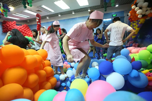 Nurses pop the balloons during a balloon fight for relieving stress at South China Mall on October 25, 2015 in Dongguan, Guangdong Province of China. Over 100 occupational staff took part in a balloon fight with about 600,000 used balloons to relieve stress on October 25 at South China Mall in Dongguan. (Photo by ChinaFotoPress/ChinaFotoPress via Getty Images)