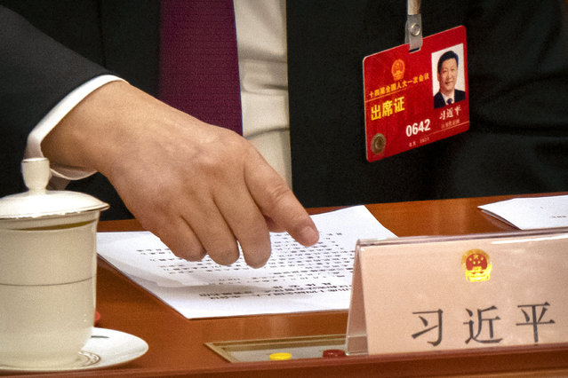 Chinese President Xi Jinping reaches to push a button to vote on a measure during a session of China's National People's Congress (NPC) at the Great Hall of the People in Beijing, Friday, March 10, 2023. Chinese leader Xi Jinping was awarded a third five-year term as president Friday, putting him on track to stay in power for life at a time of severe economic challenges and rising tensions with the U.S. and others. (Photo by Mark Schiefelbein/AP Photo)