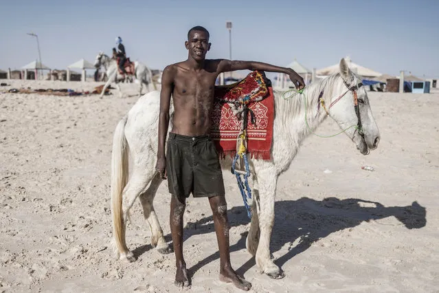 A man poses next to a horse as he enjoys an afternoon at a popular beach in the Tefargh Zeina district of Nouakchott, on March 10, 2023. (Photo by Marco Longari/AFP Photo)