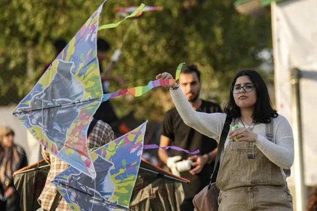 A woman launches a Kite during Baghdad Kite Festival in Baghdad, Iraq, Friday, March 17, 2023. (Photo by Hadi Mizban/AP Photo)