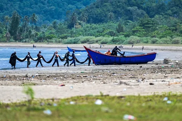 Fishermen load their nets at a beach in Lhoong, Indonesia's Aceh province on March 21, 2023. (Photo by Chaideer Mahyuddin/AFP Photo)