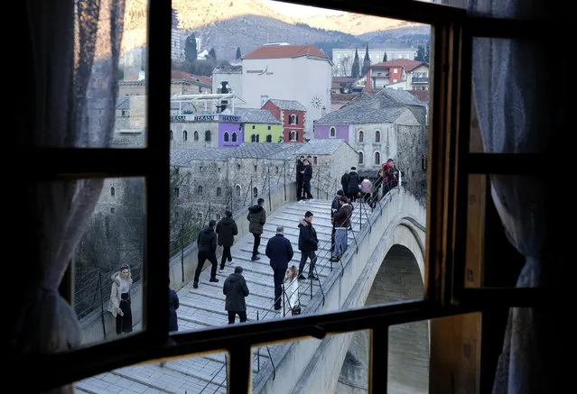 People walk over the historic Old bridge in Mostar, Bosnia, Sunday, December 20, 2020. Divided between Muslim Bosniaks and Catholic Croats, who fought fiercely for control over the city during the 1990s conflict, Mostar has not held a local poll since 2008, when Bosnia's constitutional court declared its election rules to be discriminatory and ordered that they be changed. (Photo by Kemal Softic/AP Photo)