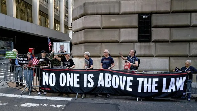 Protesters gather before former President Donald Trump arrives in a motorcade for a deposition in New York Thursday, April 13, 2023. (Photo by Craig Ruttle/AP Photo)