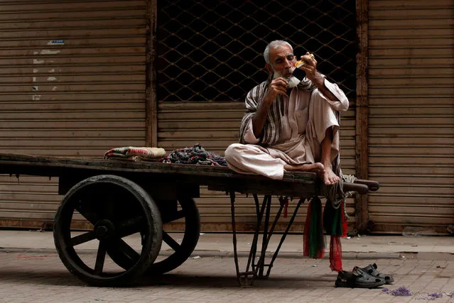 A labourer trims his moustaches while waiting for a work on his push-cart along a wholesale market in Karachi, Pakistan February 26, 2018. (Photo by Akhtar Soomro/Reuters)