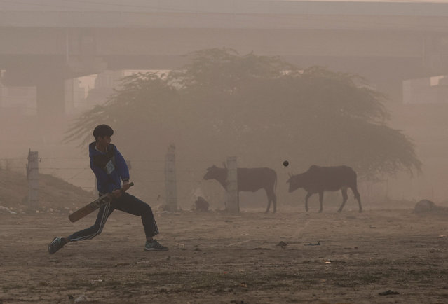 A boy plays cricket on a ground near the banks of Yamuna river, on a smoggy morning, amid ongoing air pollution in New Delhi, India, on November 13, 2025. (Photo by Anushree Fadnavis/Reuters)