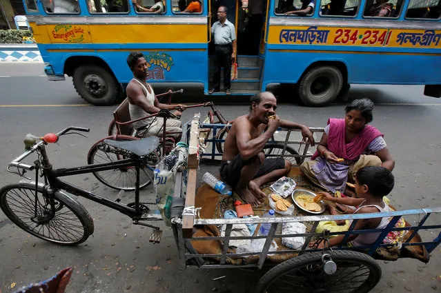 A tricycle puller's family eats on a busy road in Kolkata, May 10, 2018. (Photo by Rupak De Chowdhuri/Reuters)