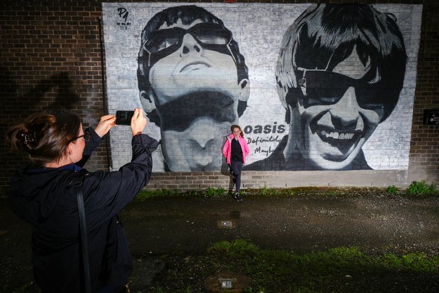 Oasis fans photograph a new mural depicting Liam and Noel Gallagher of Oasis, created by Manchester street artist Pic.One.Art., on the side of the Sifters Record store in Burnage on August 28, 2024 in Manchester, England. Brothers Liam and Noel Gallagher, estranged for over 15 years, have announced they are due to reunite their band Oasis for a series of concerts next summer. The Manchester band had a string of hits in the 1990's including Wonderwall, Champagne Supernova and Don't Look Back In Anger.  (Photo by Christopher Furlong/Getty Images)