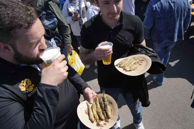 Men carry fried smelts during a traditional smelt fish gastronomic festival in the city of Novaya Ladoga (New Ladoga), 125 km (77 miles) east of St. Petersburg, Russia, Saturday, May 13, 2023. (Photo by Dmitri Lovetsky/AP Photo)