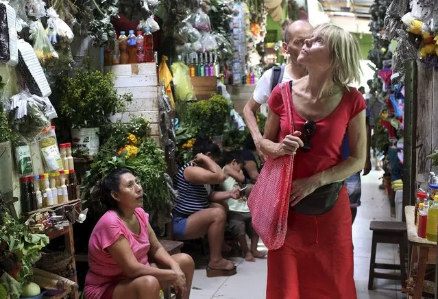 In this May 4, 2018 photo, foreign tourists look for souvenirs and ayahuasca in the Pucallpa market, deep in the Amazonian jungle of Peru. The tourist trail to the spiritual use of ayahuasca by Westerners took off with the publication in 1963 of “The Yage Letters”, in which beatnik poet Allen Ginsberg described feeling like a “snake vomiting out the universe” after trying ayahuasca in the Colombian rainforest. (Photo by Martin Mejia/AP Photo)