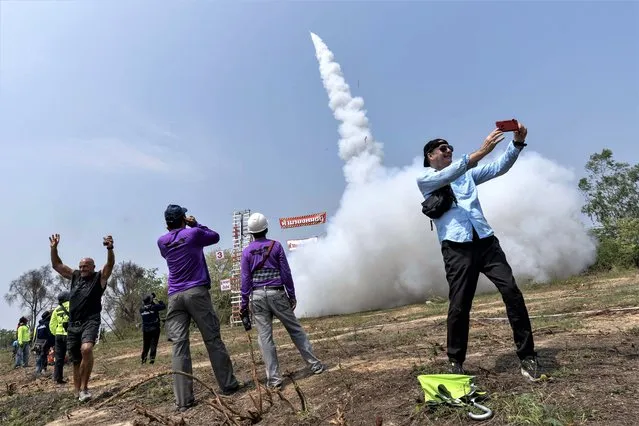 Festival goers watch as a homemade sen class rocket flies into the air in a field in Yasothon, Thailand on May 21, 2023 during the annual Issan rocket festival. The festival culminates with the launching of dozens of large homemade rockets, believed in times past to hasten the coming of the rainy season. The city of Yasothon is known for having the largest bun bang fai festival, with smaller events taking place throughout northeast Thailand. (Photo by Adryel Talamantes/ZUMA Press Wire/Rex Features/Shutterstock)