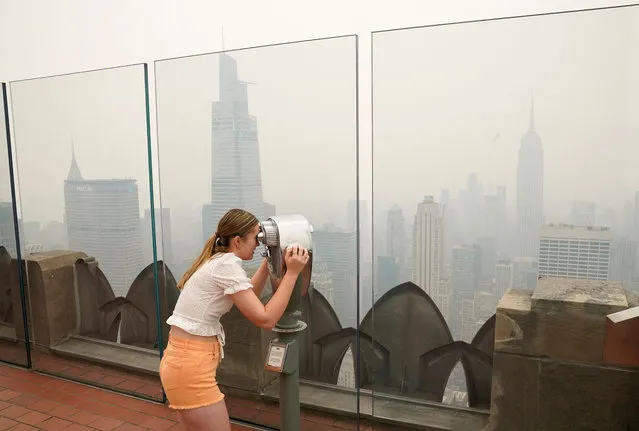 Niamh Farley from Ireland looks out at Midtown Manhattan in the haze from the Top of the Rock NYC Observation Deck at Rockefeller Center on June 7, 2023. Smoke from Canada’s wildfires has engulfed the Northeast and Mid-Atlantic regions of the US, raising concerns over the harms of persistent poor air quality. (Photo by Timothy A. Clary/AFP Photo)