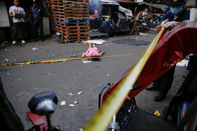 Policemen investigate near the body of a woman killed by unknown gunmen at the market in a port area of Manila, Philippines October 28, 2016. (Photo by Damir Sagolj/Reuters)