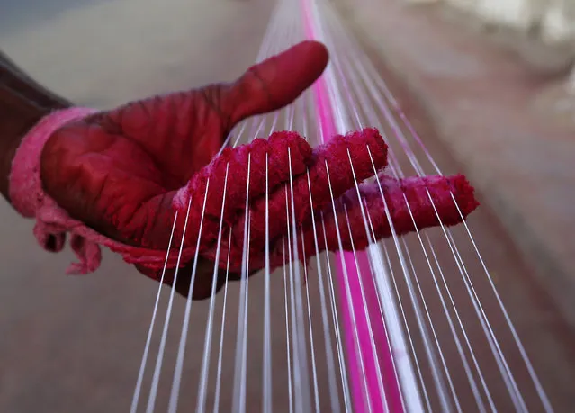 A worker applies colour to strings which will be used to fly kites, by a roadside in Ahmedabad, India, December 14, 2015. (Photo by Amit Dave/Reuters)