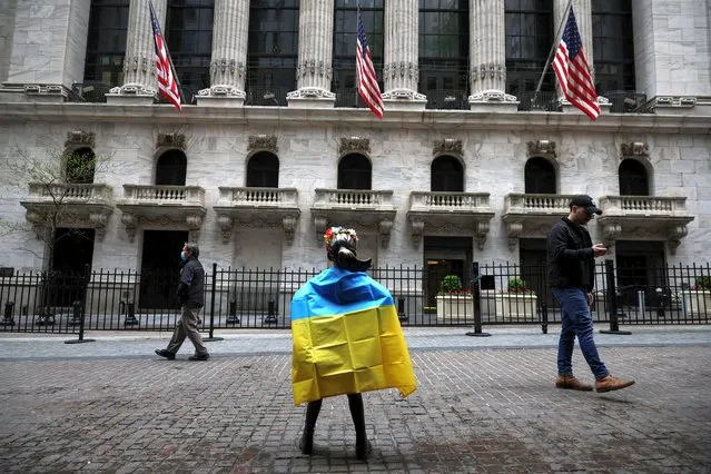 The Fearless Girl Statue by artist Kristen Visbal stands draped in the flag of Ukraine, as the Russian invasion of Ukraine continues, after a demonstration outside the New York Stock Exchange in New York City, U.S., May 4, 2022. (Photo by Shannon Stapleton/Reuters)