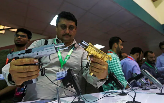 A visitor compares pistols during the International Defence Exhibition and Seminar “IDEAS 2016” in Karachi, Pakistan, November 23, 2016. (Photo by Akhtar Soomro/Reuters)