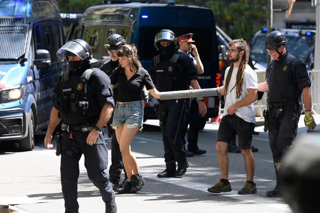 Police officers detain students who chained themselves to protest against a measure imposing 25% of classes to be taught in Castillan language in Catalonia's schools, in front of the Government Delegation building, in Barcelona on May 16, 2022. (Photo by Josep Lago/AFP Photo)