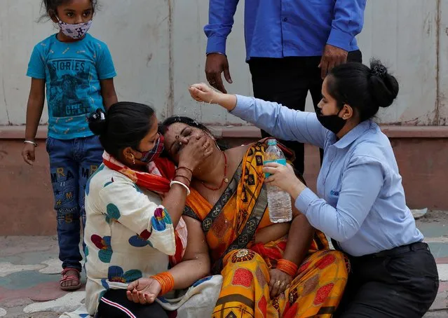 A woman is consoled after her husband died due to the coronavirus disease (COVID-19) outside a mortuary of a COVID-19 hospital in New Delhi, India, April 15, 2021. (Photo by Danish Siddiqui/Reuters)