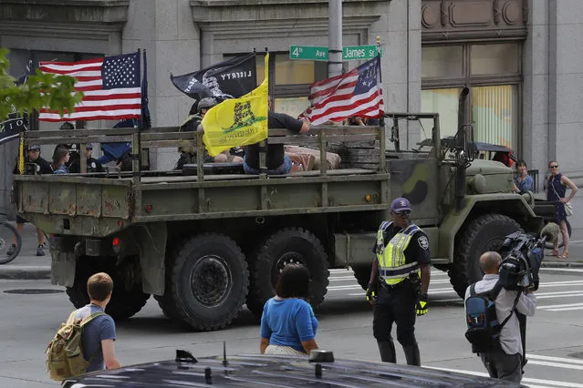 Supporters of a rally held by members of Patriot Prayer and other groups advocating for gun rights ride in a military-style truck, Saturday, August 18, 2018, near City Hall in Seattle. (Photo by Ted S. Warren/AP Photo)